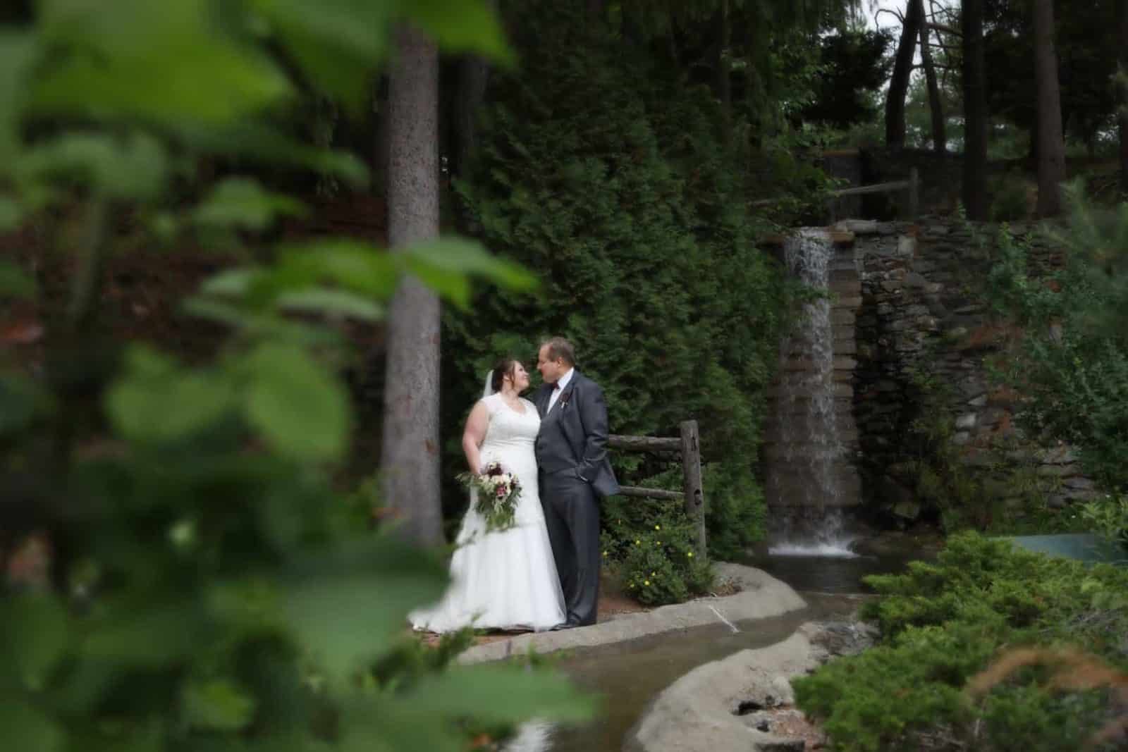 Bride and groom looking at one another near waterfall and stone walk way