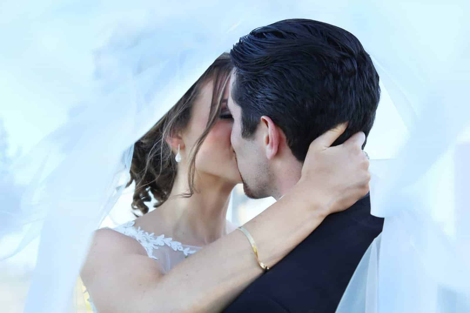 bride and groom kissing under brides vail