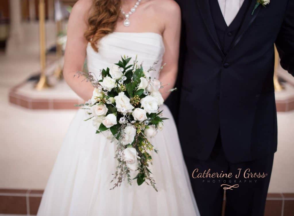 Brie and groom facing camera, picture from the waist down, bride holding wedding bouquet 