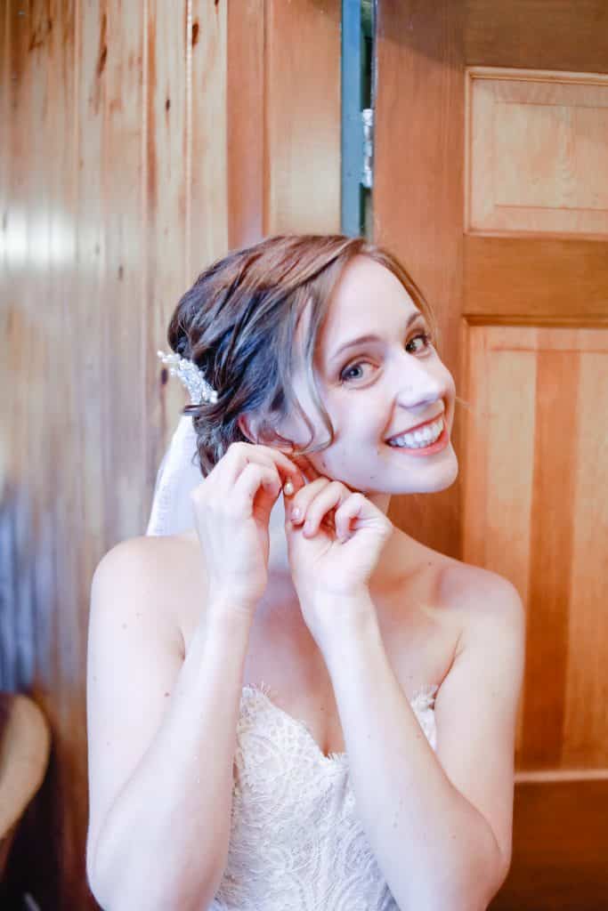 bride getting ready looking at the camera putting on her earings