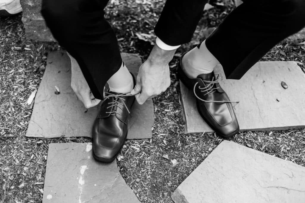 groom tieing his shoes, black and white