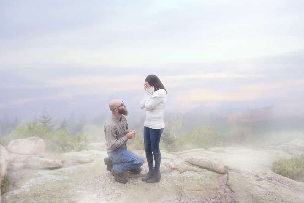 man on one knee proposing to his girlfriend, fog, top of cadillac mountain, maine