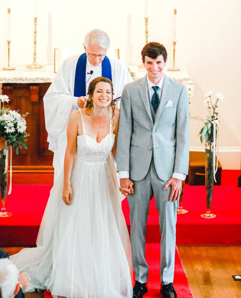 bride and groom looking at the camera, holding hands as a married couple