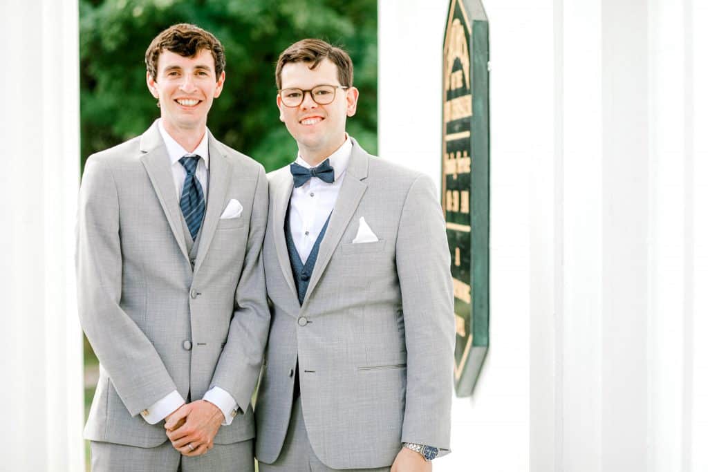 Groom and best man portrait facing the camera with white pillars on both sides