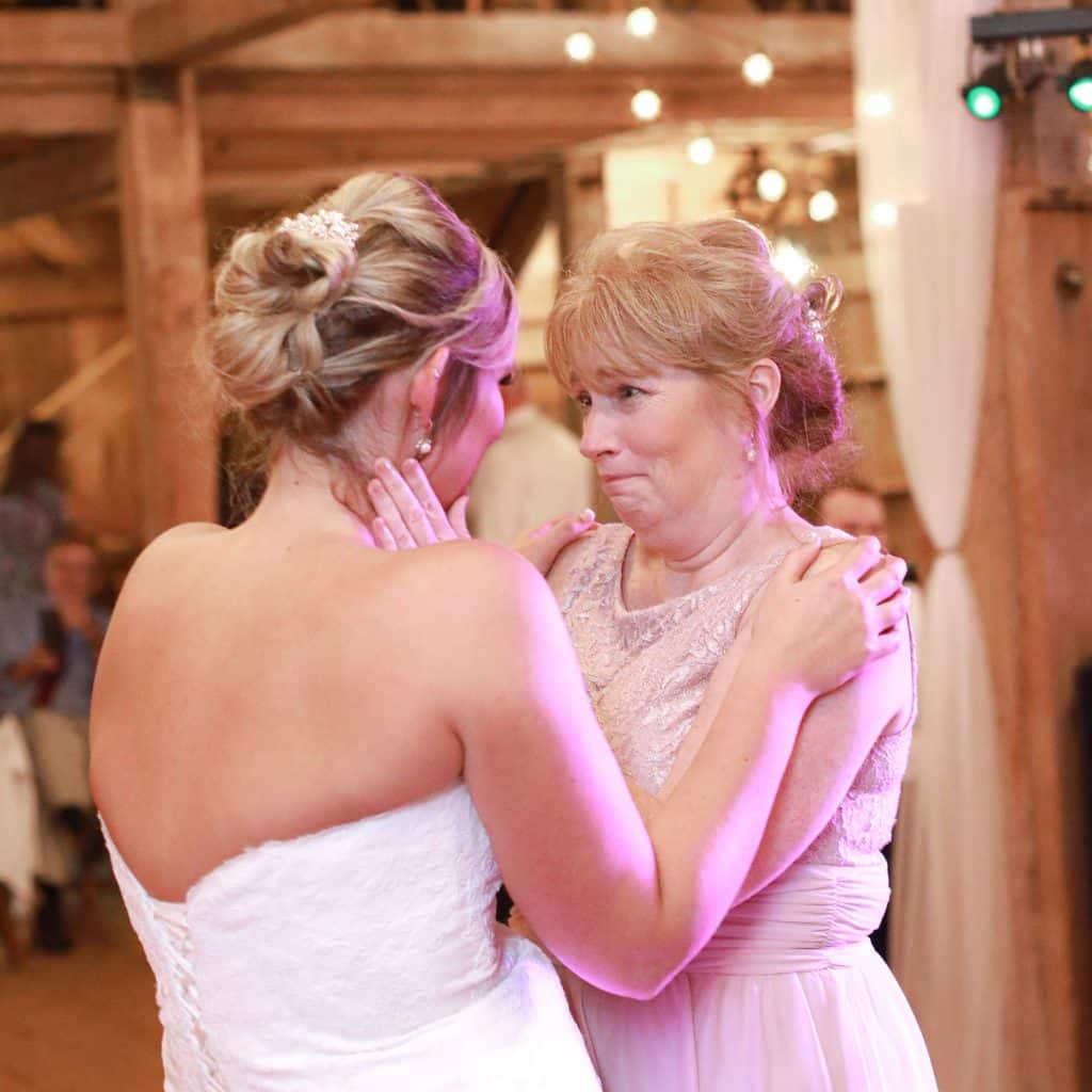 mother crying looking at ehr daughter the bride during their first dance