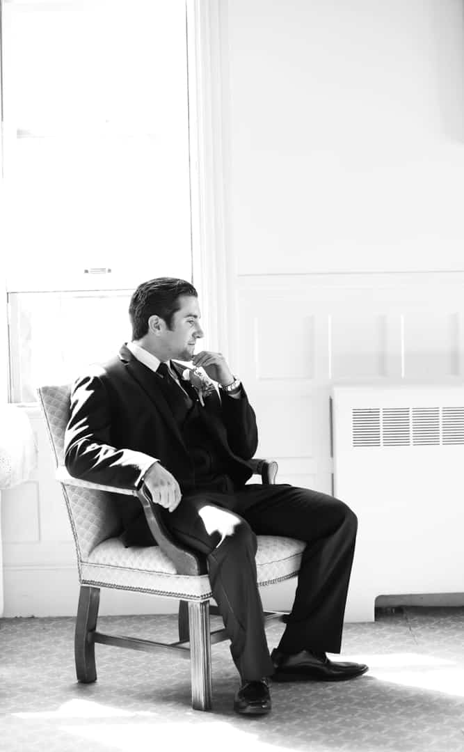 Groom sitting in chair, black and white