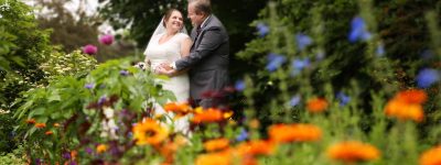 bride and groom looking at each other in park with flowers