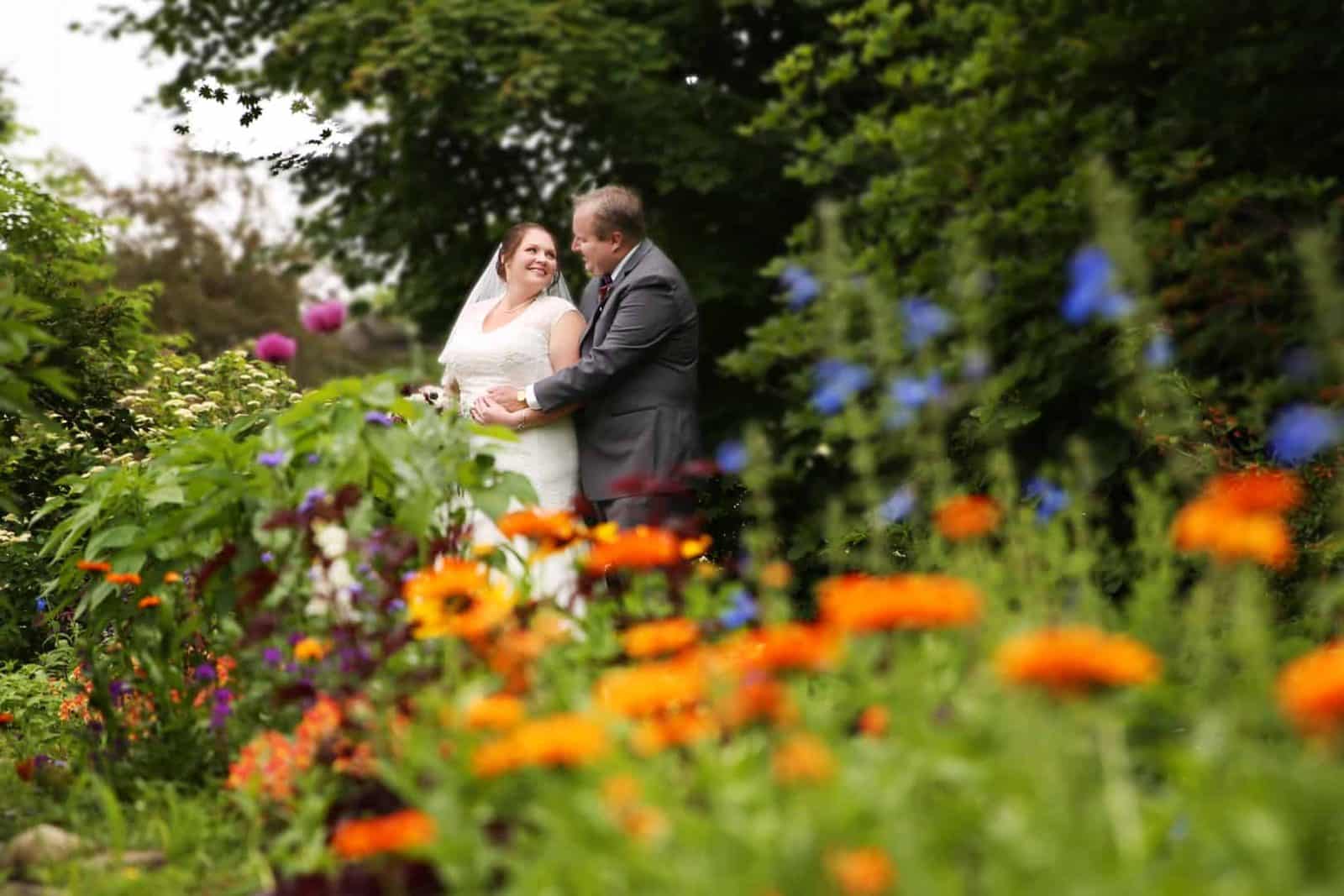 bride and groom looking at each other in park with flowers