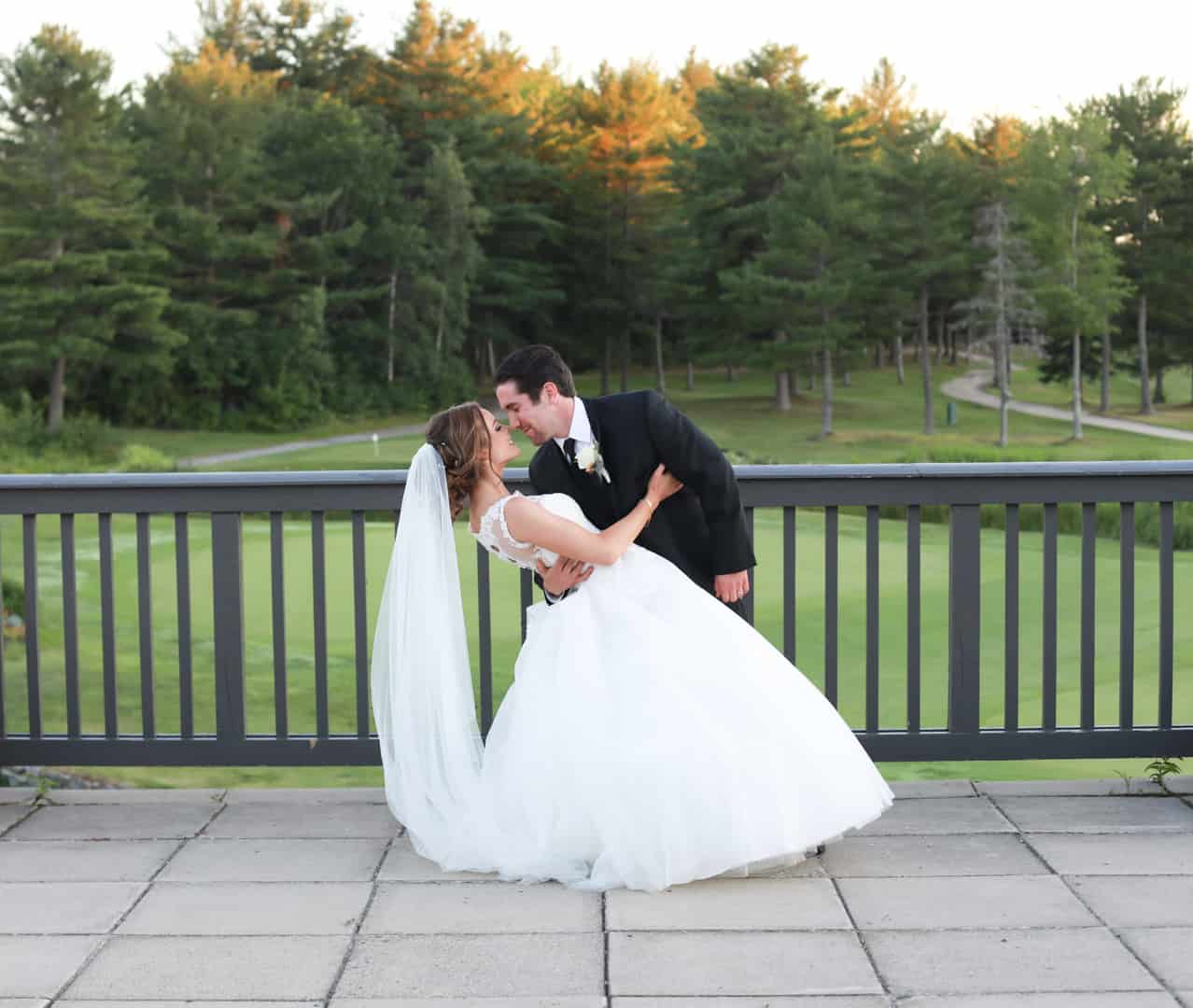 groom dipping bride for a kiss on the balcony overlooking got course.