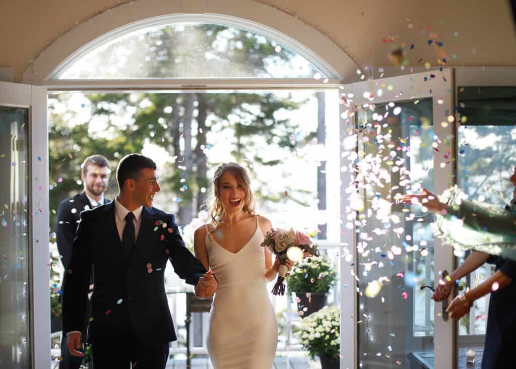 Confetti flying as the bride and groom come in as a newly wed couple 