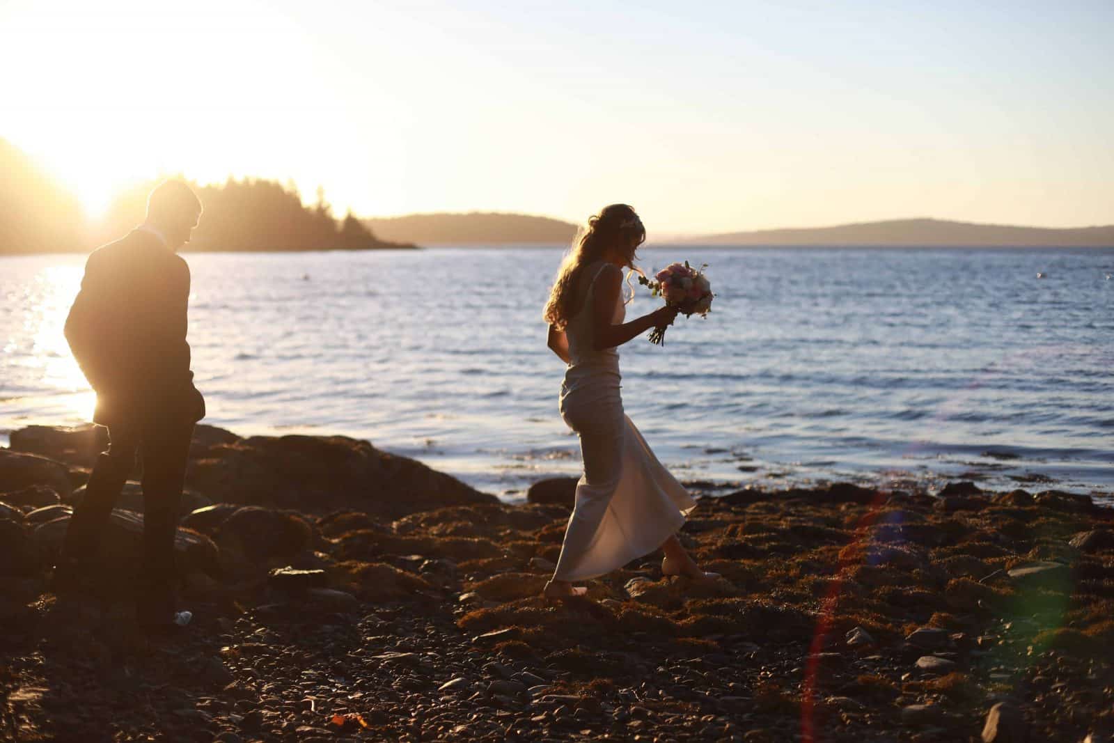 bride and groom walking on the beach, sunset, blue ocean