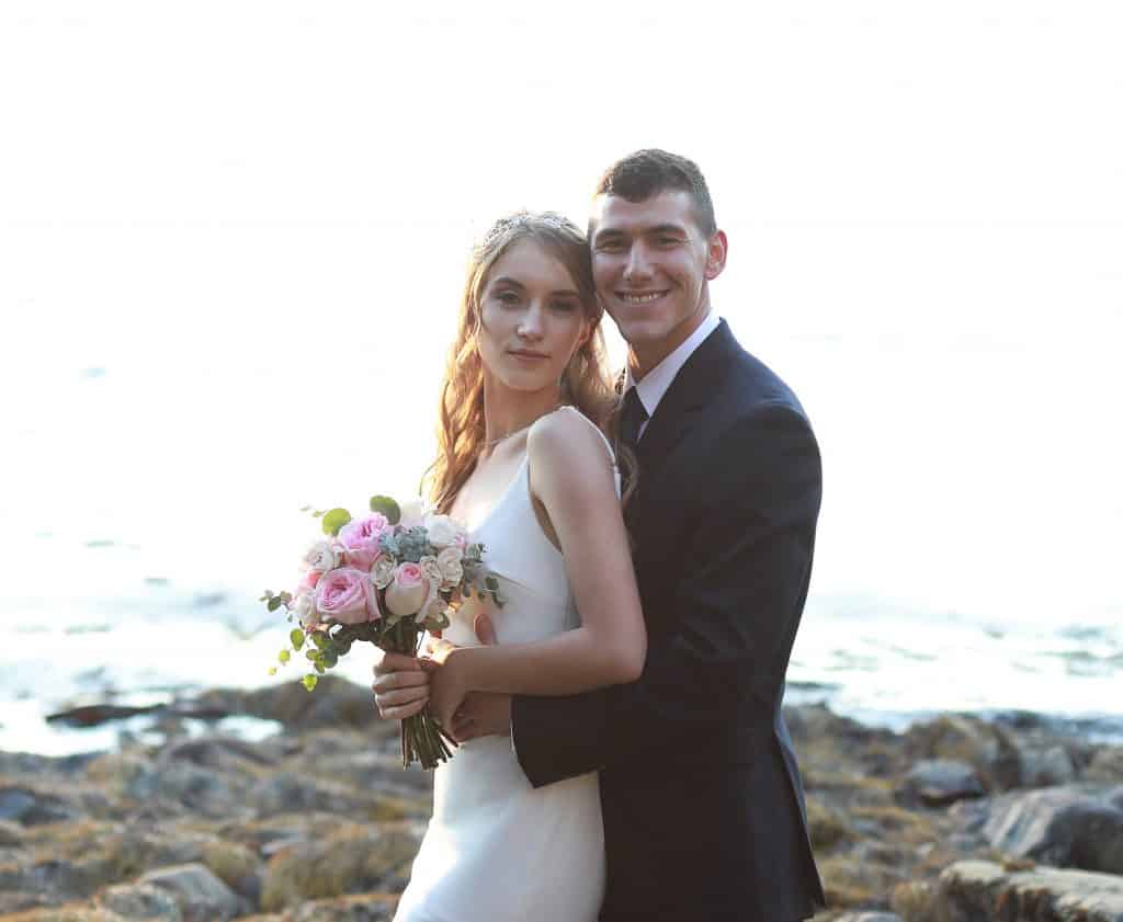 bride and groom hugging eachother on the beach overlooking the ocean