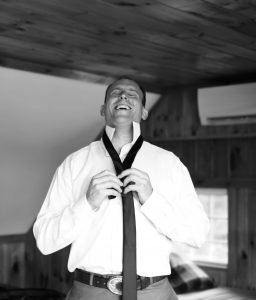 Groom tying his tie in black and white