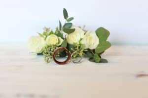 Boutonniere, wedding rings, on a white bench 