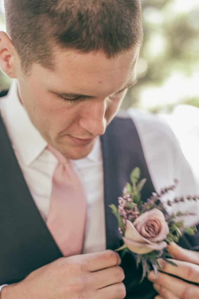 groom getting ready looking down at his boutineer