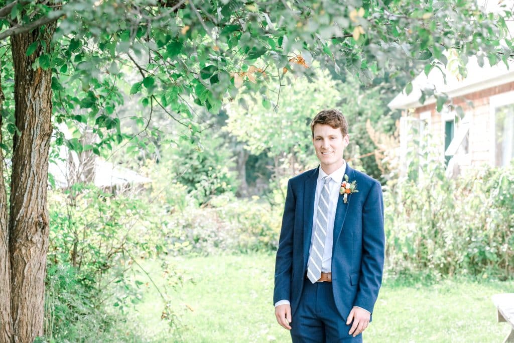 groom looking at the camera smiling waiting for his first look