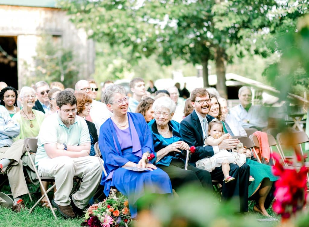 mother and grandmother of the bride watching her get married and smiling.