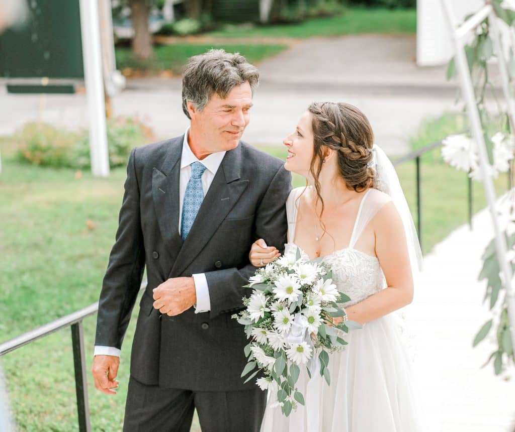 bride looking at her stepfather arm in arm before being walked down the aisle