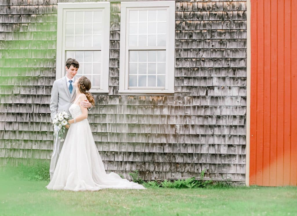 Bride and groom holding each other and looking at each other in front of the barm