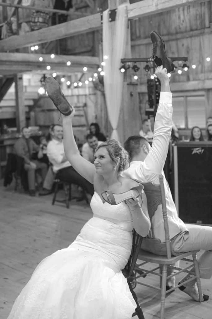 wedding reception shoe game. Bride and groom sitting in chairs holding up shoes to answer questions