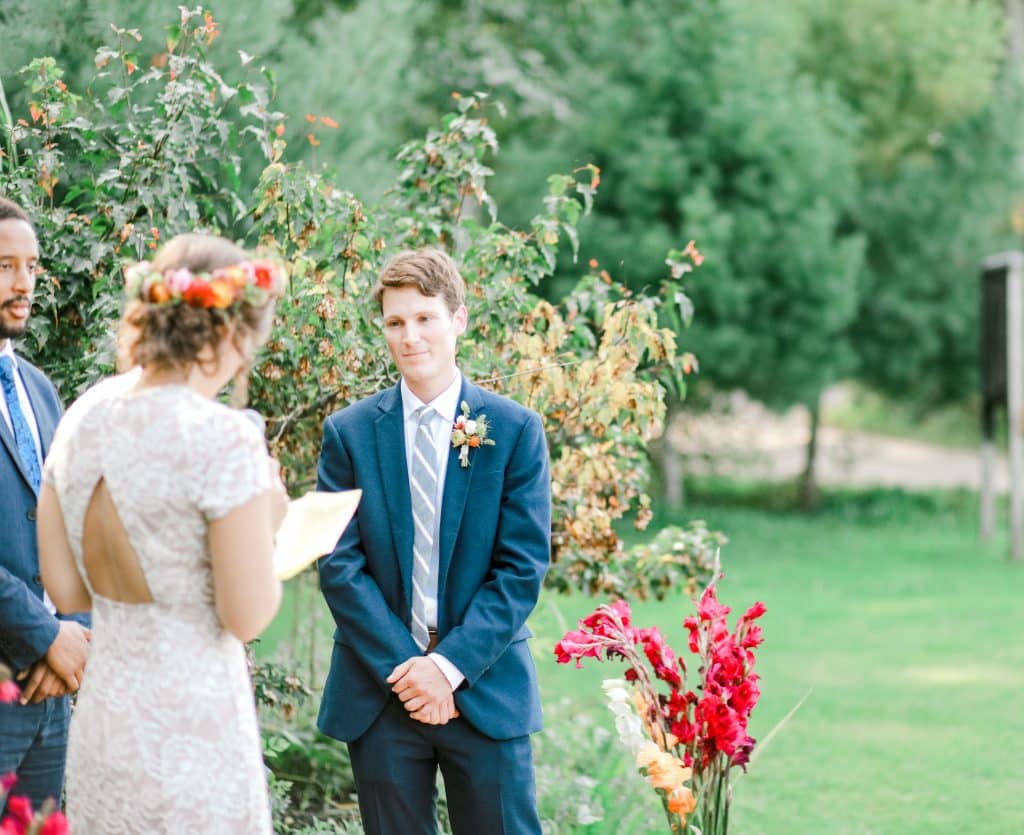 bride reading her vows to her groom at the alter, looking at the grooms face.