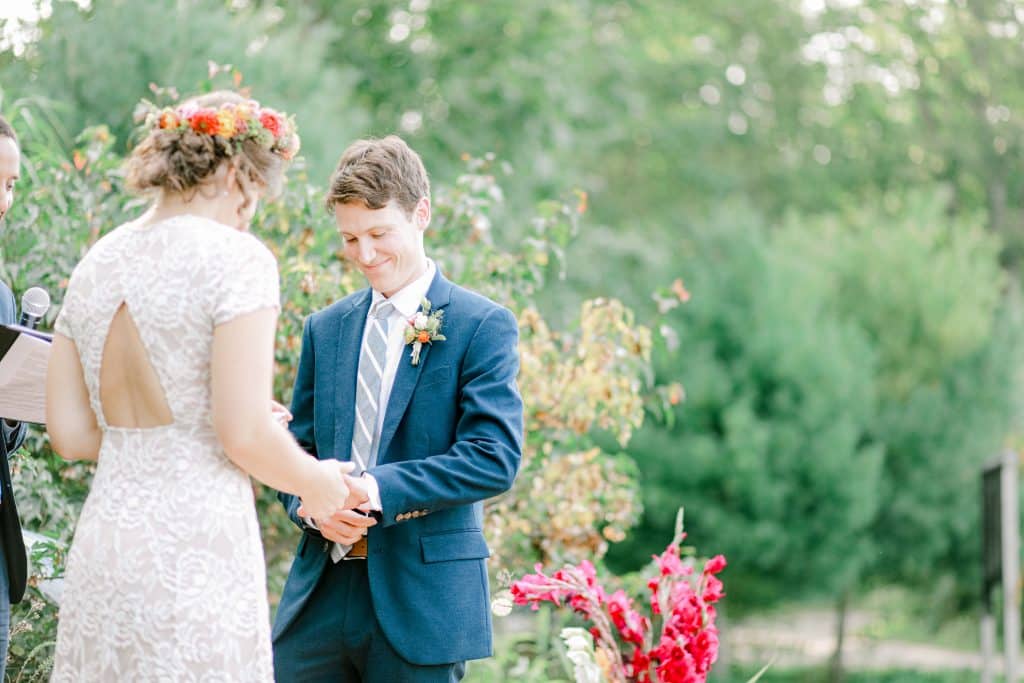 bride and groom at the alter holing hands smiling and looking down