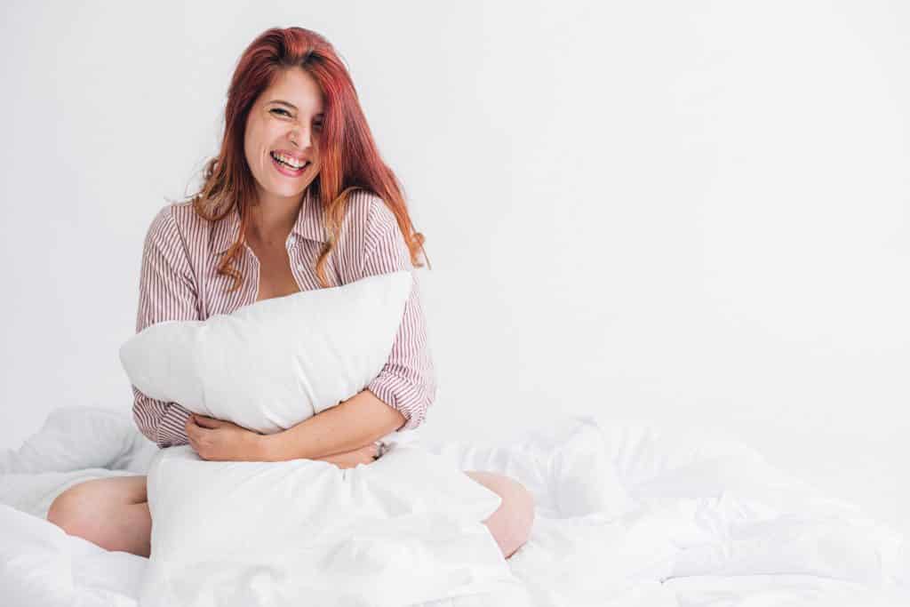 woman in pink t-shirt hugging a pillow in studio