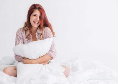 woman in pink t-shirt hugging a pillow in studio