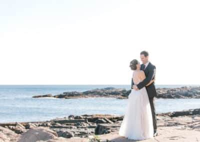 bride and groom on rocky maine beach