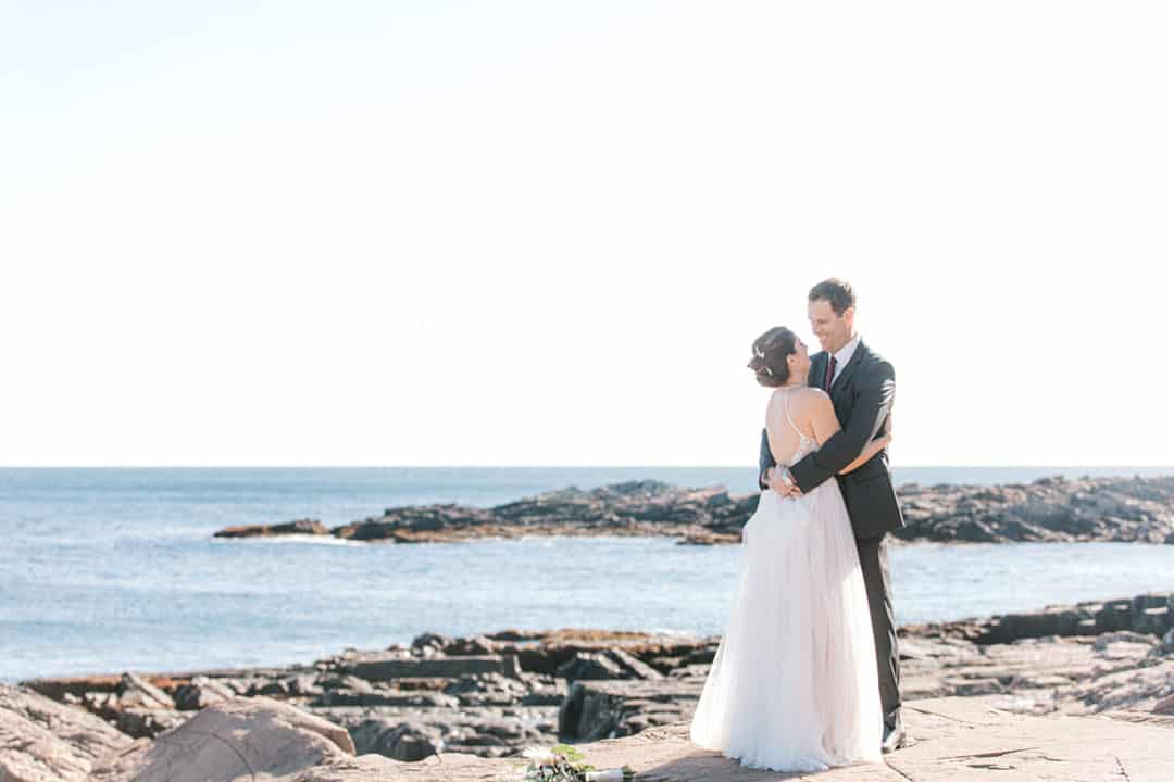 bride and groom on rocky maine beach