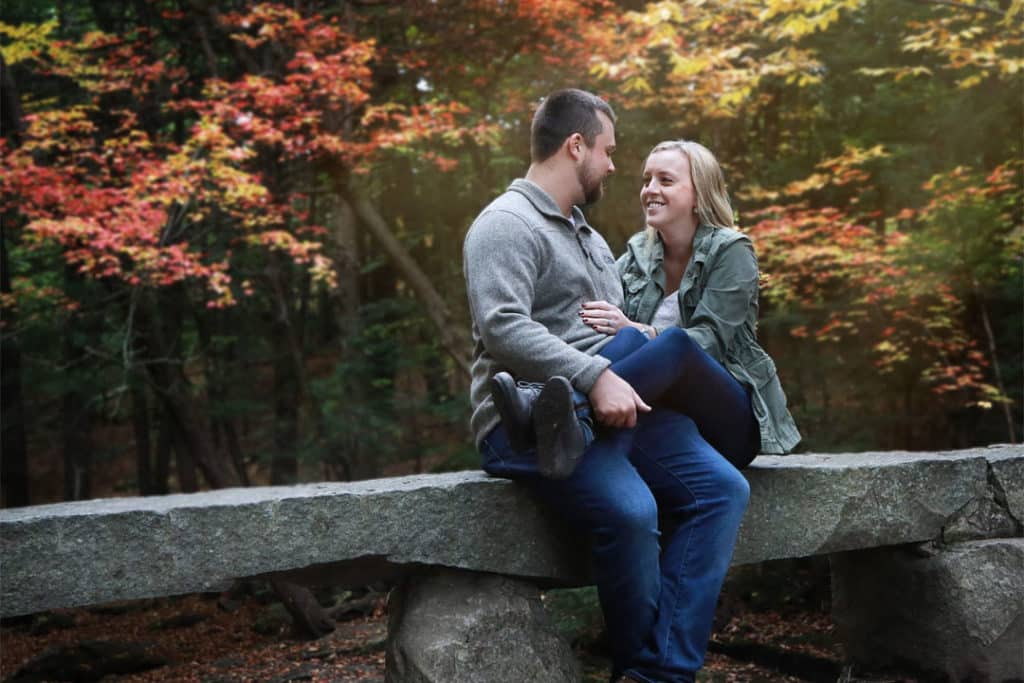 engaged couple sitting on a bridge in maine