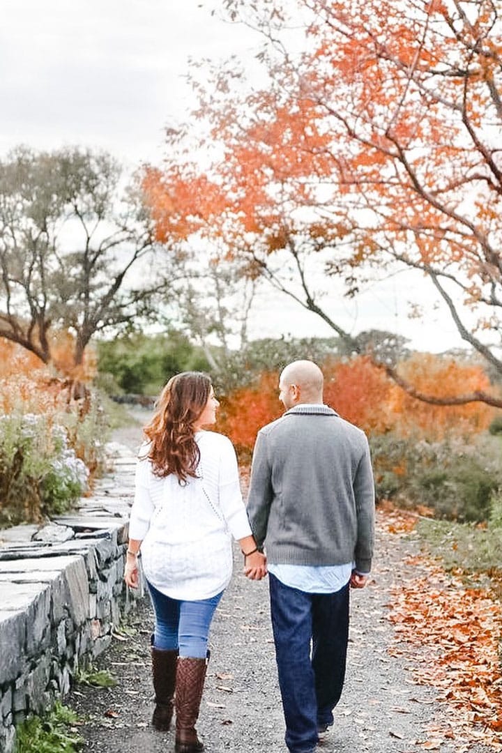 photo of engaged Maine couple walking down a path in fall