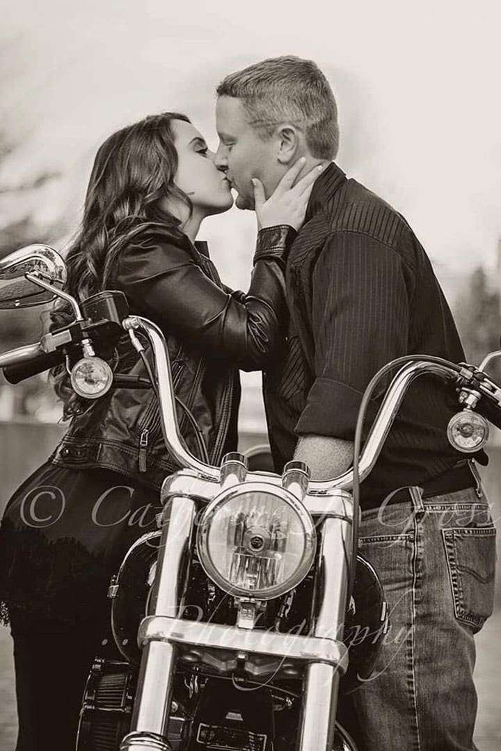 black and white engagement photo of engaged couple kissing on motorcycle in Maine
