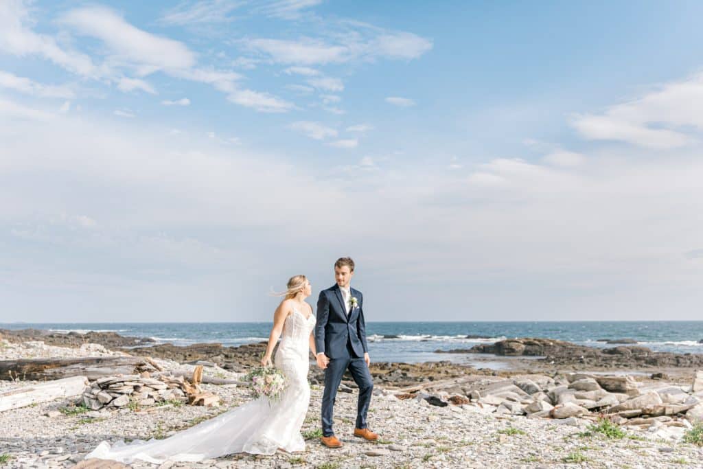 Bride and groom walk the rocky beach on Peaks Island 