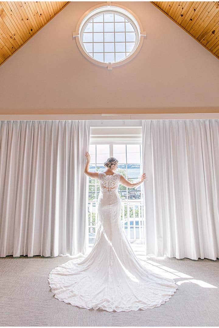 bride poses for kennebunkport wedding photographer in front of french doors