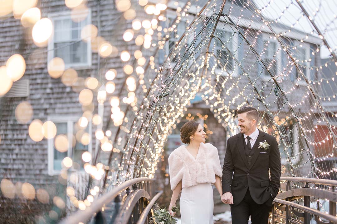 newly wed couple walking under lit archway by Catherine J. Gross