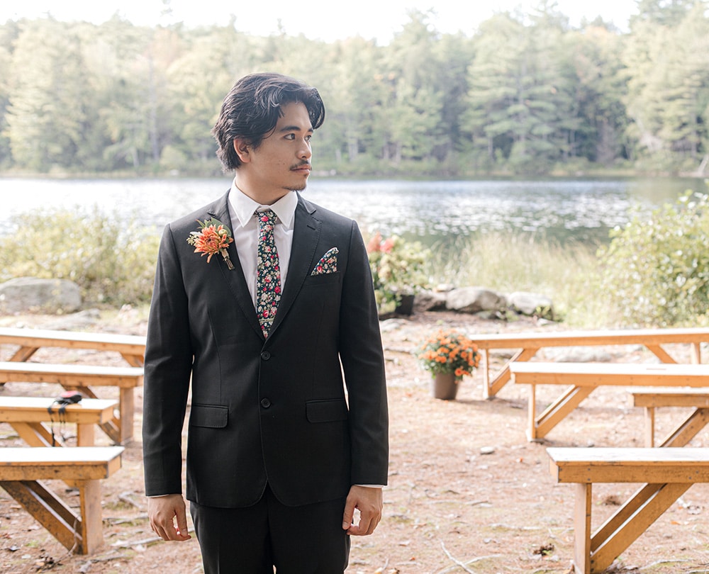 groom before the wedding standing in the aisle with a Maine lake in the background