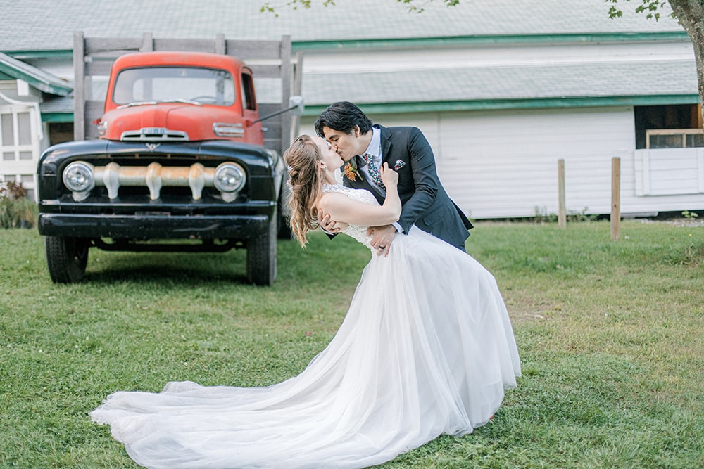 groom tipping bride in front of antique pickup truck
