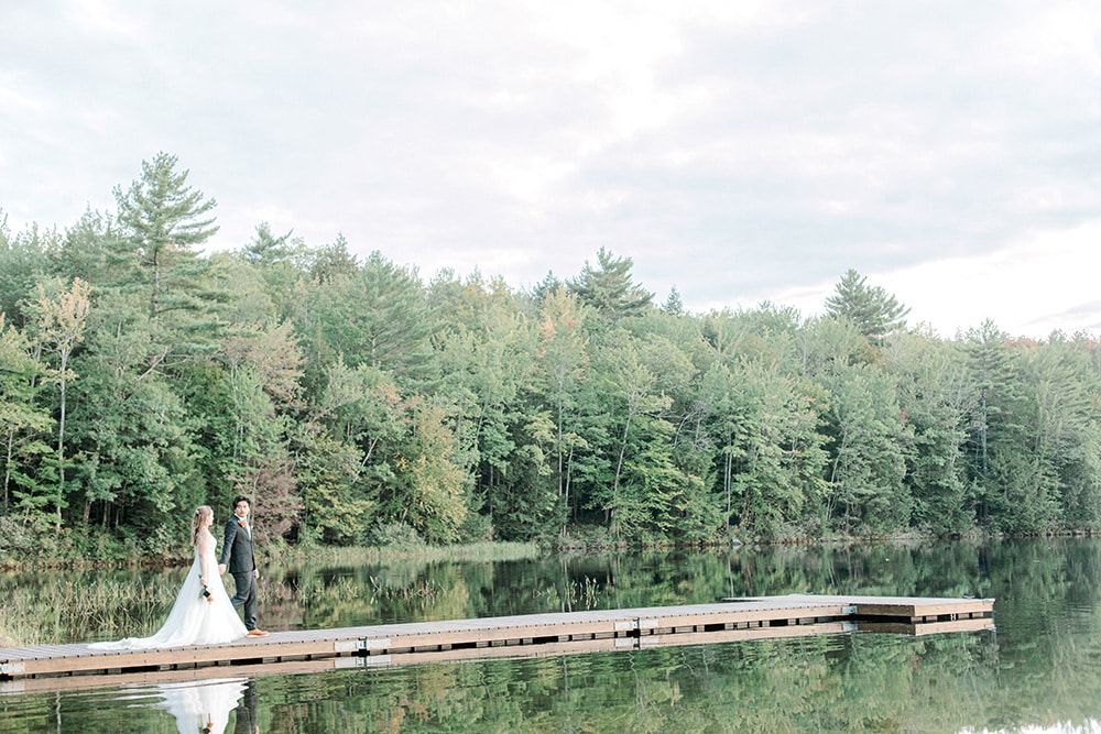 bride and groom walking out on a dock on a private maine lake wedding
