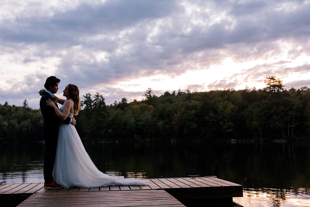 bride and groom on maine lake during sunset