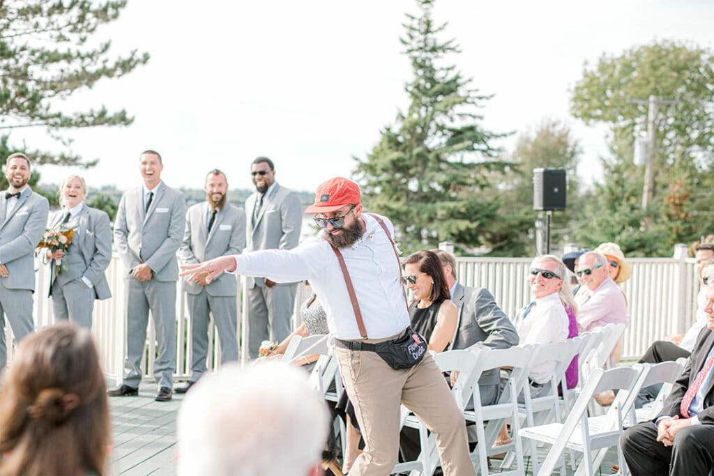 flower boy/man sprinkling flower petals on the aisle of a spruce point inn wedding