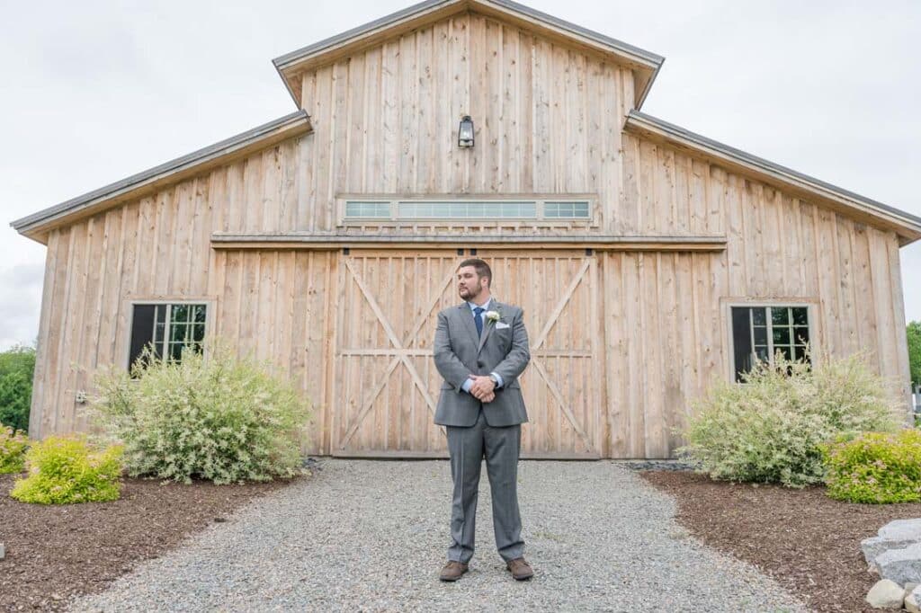 Groom posing confidently in front of the rustic barn at The Grove.