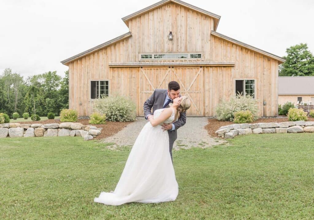 Bride and groom sharing a romantic kiss in front of the barn.