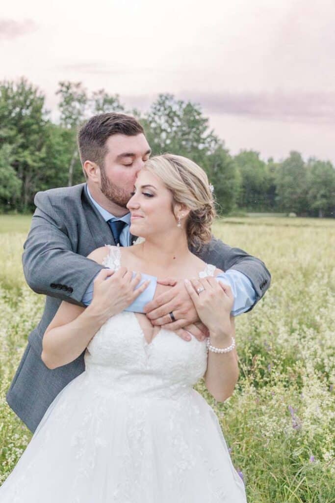 Groom kissing his bride's forehead in an intimate moment.