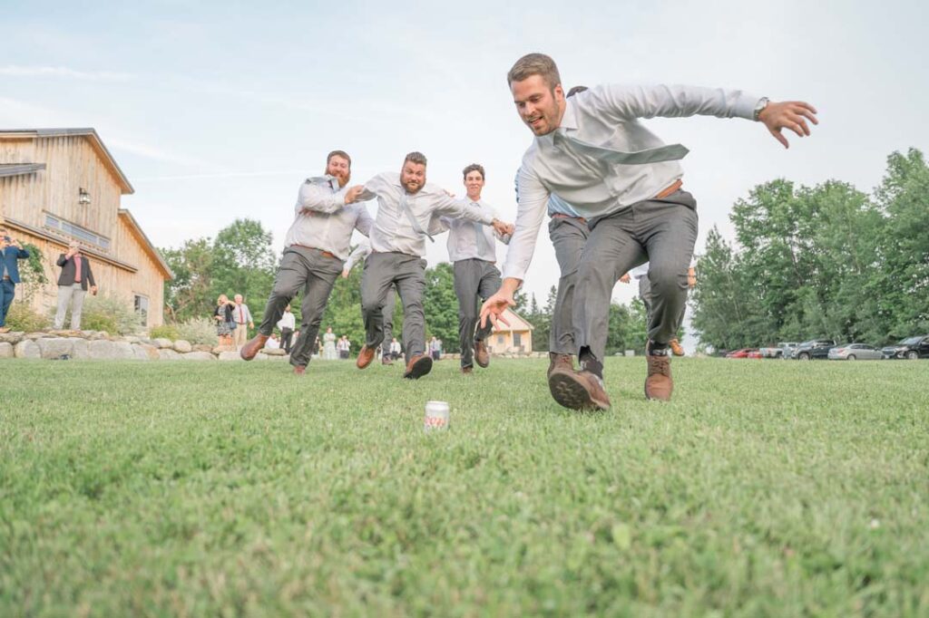 Groomsmen sprint towards a beer can in a lighthearted competition.