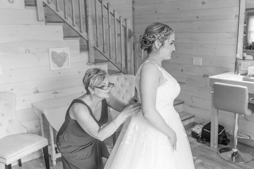 Bride's mother helping her daughter into her wedding gown.