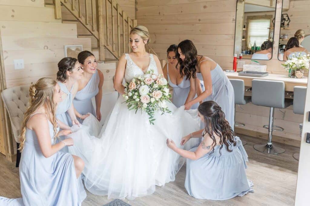 Bridesmaids assisting the bride with her dress