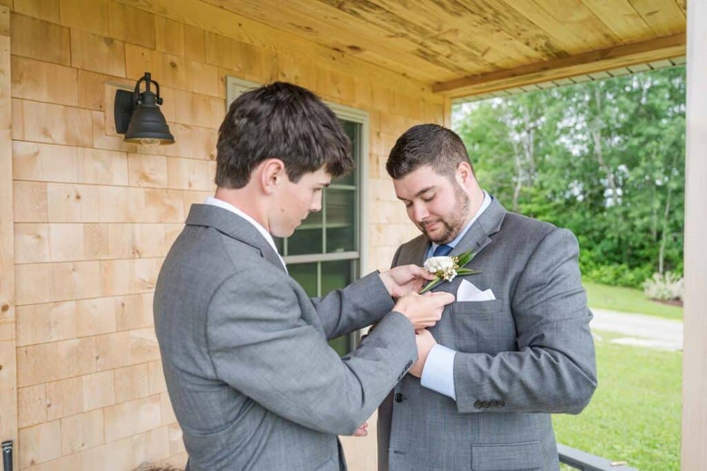 Groom and best man adjusting the boutonniere.